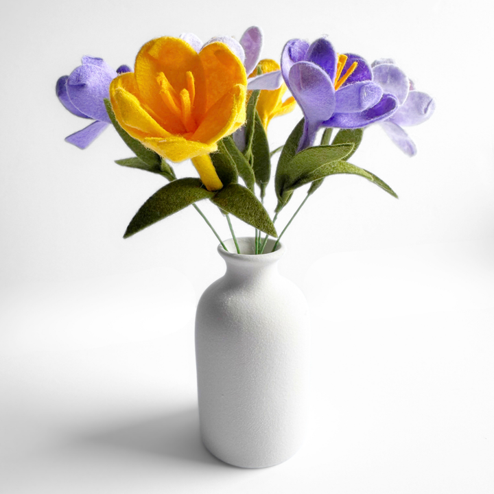 Felt crocus flowers in a white vase on a light background