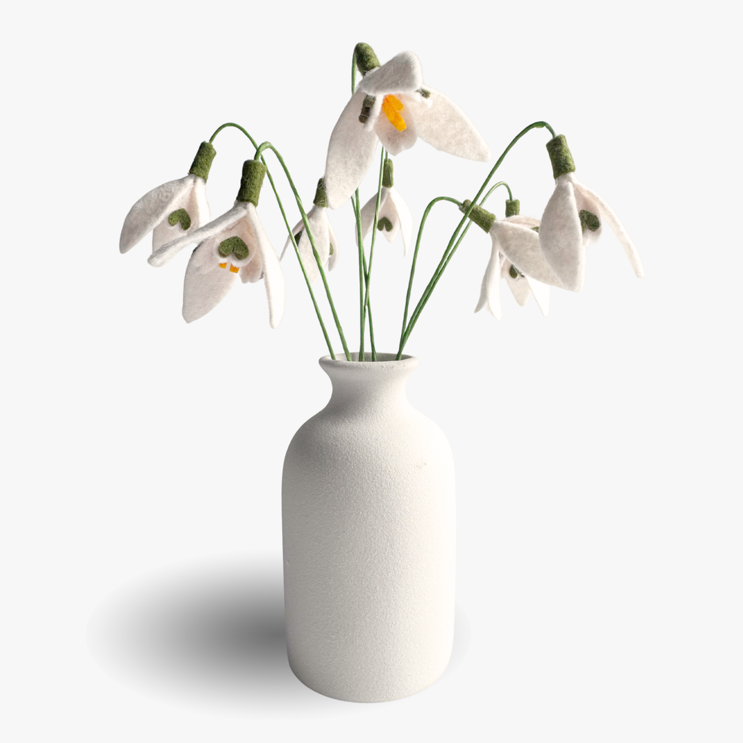 White vase with felt snowdrop flowers on a white background
